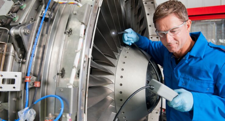 engineer inspecting the turbine engine of a passenger jet at a hangar.